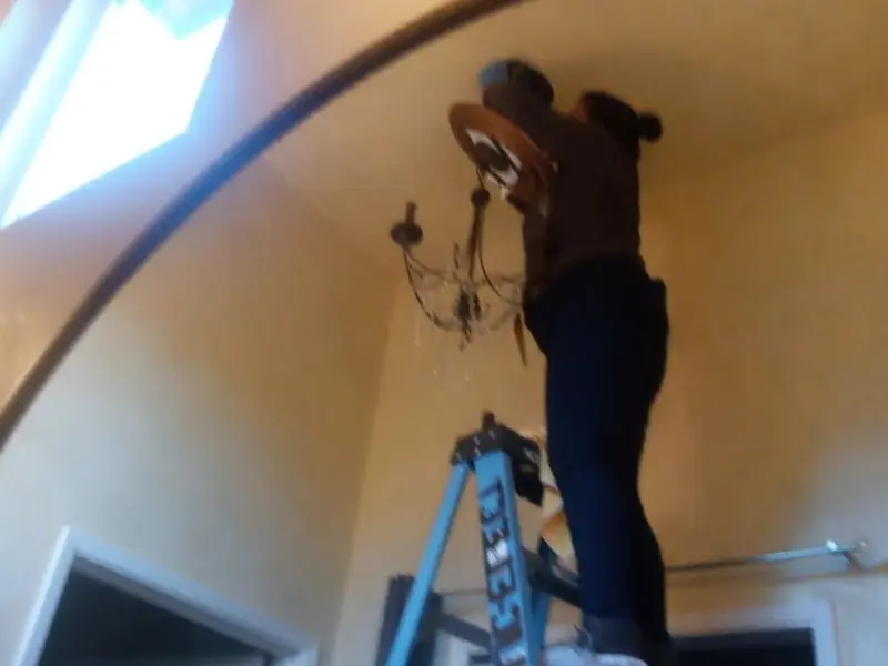 Electrician installing a chandelier in a Bow residence